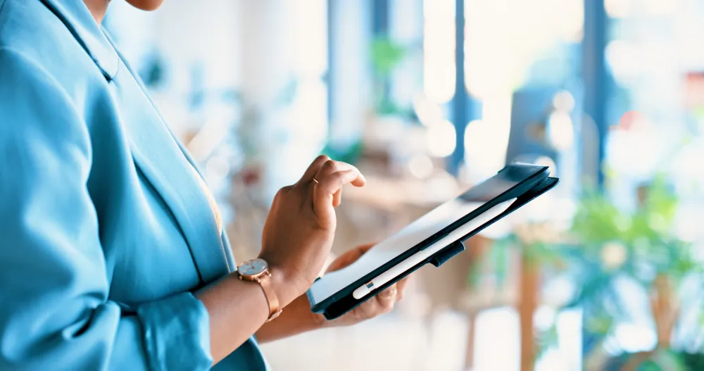 A person holding a tablet with their hand hovering over the screen