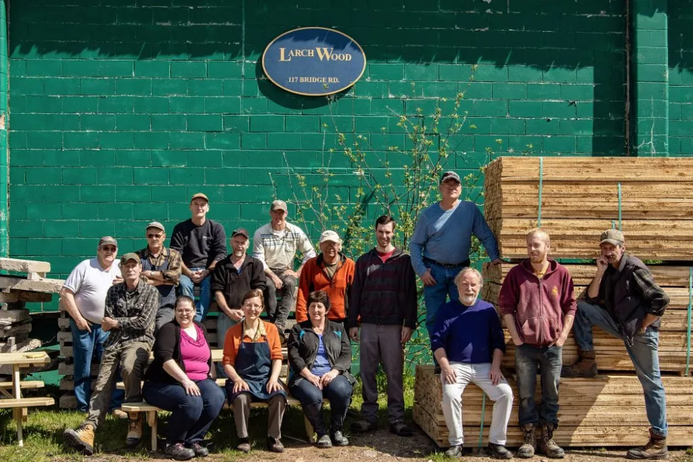 Staff members posting outdoors underneath Larch Wood signage