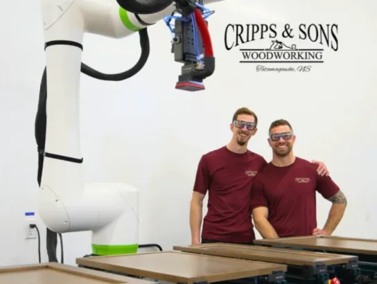 Two men standing behinf woodworking machinery