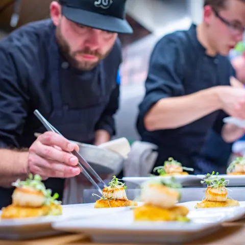 An image of a chef plating a fine dining dish.
