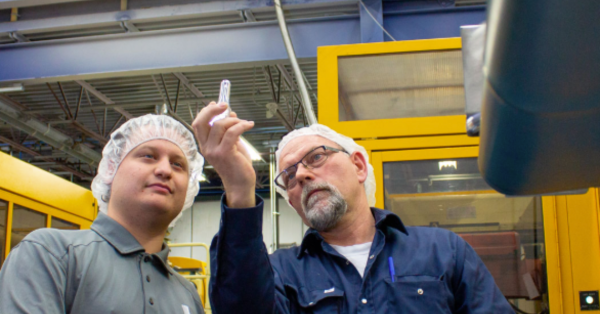 Two men looking at tube of recycled plastic