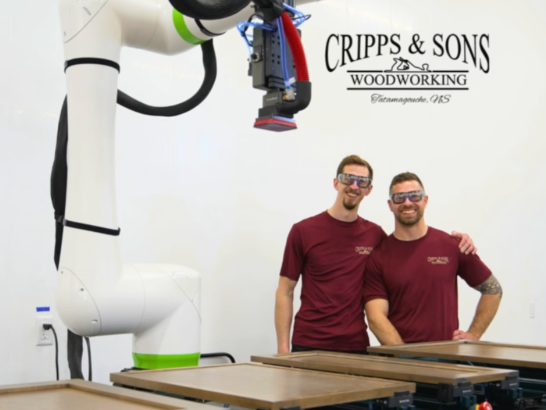 Two men standing behinf woodworking machinery