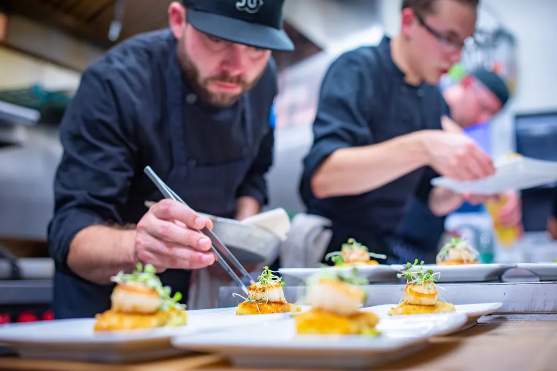 An image of a chef plating a fine dining dish.